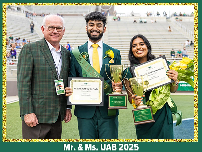 Three people stand together in a stadium, with two of them, a man and woman, holding trophies and certificates labeled "Mr. & Ms. UAB 2025."
