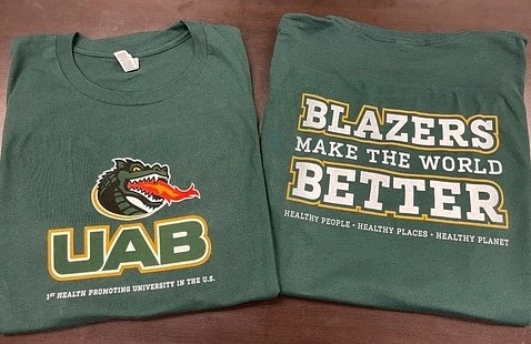 Two green T-shirts feature the UAB logo with a dragon and the slogan "Blazers Make the World Better."